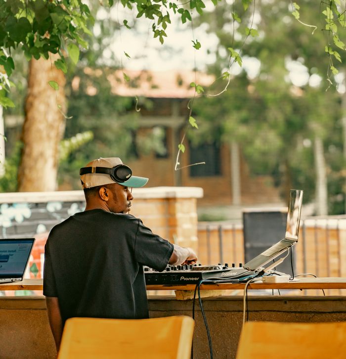 gallery-6 A DJ wearing headphones playing music on a console outdoors in a lively setting.