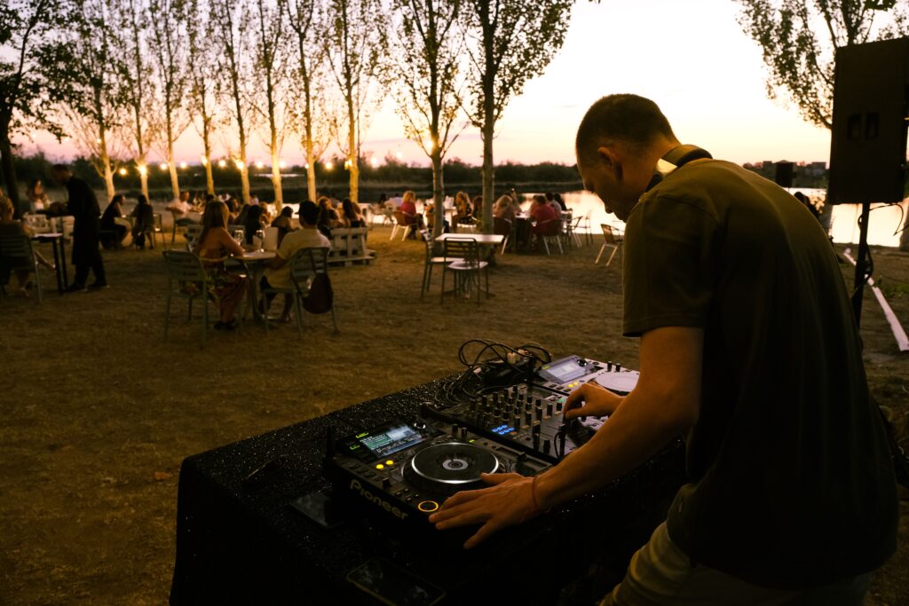 pexels photo 13902049 13902049 An outdoor party with a DJ playing music by a lakeside at sunset, creating a vibrant atmosphere.