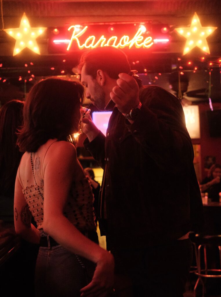 pexels photo 28651424 28651424 A couple enjoying a lively karaoke night in a dimly lit bar setting with neon lights.